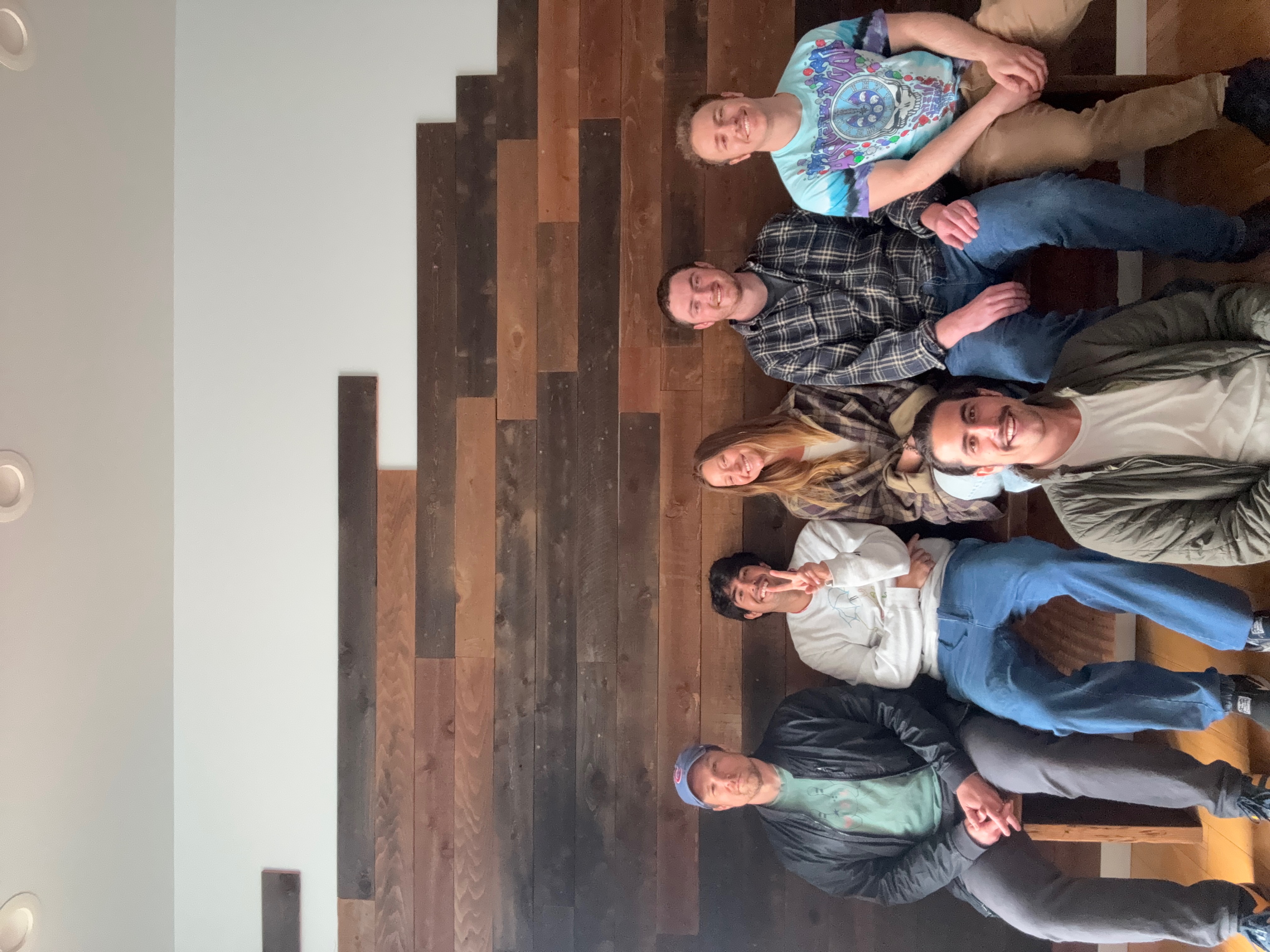 The Unbroken Chain band members sitting together in front of a reclaimed wood wall